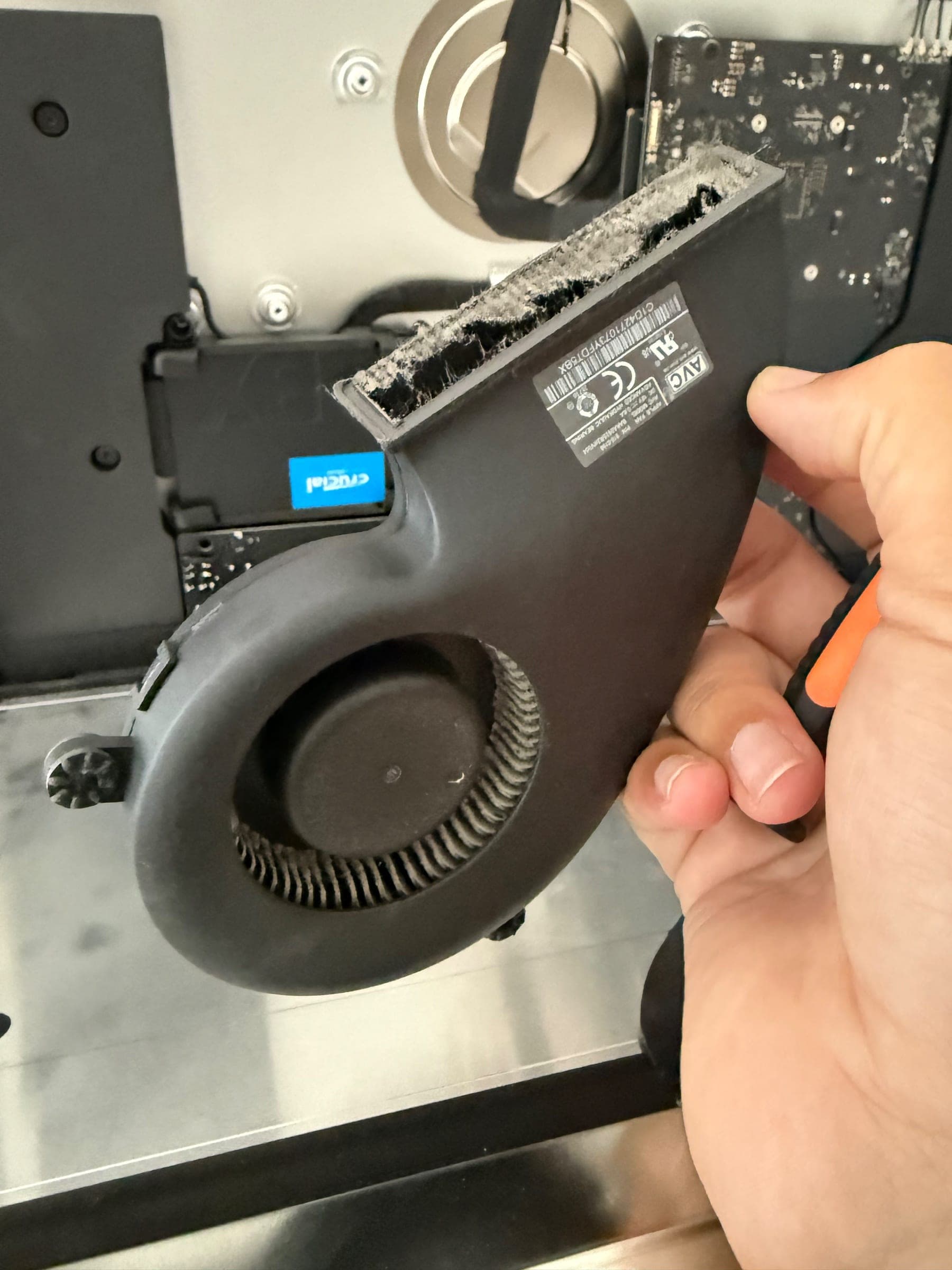Cooling fan removed from an iMac, held in hand, with a thick layer of dust caked along the intake edge