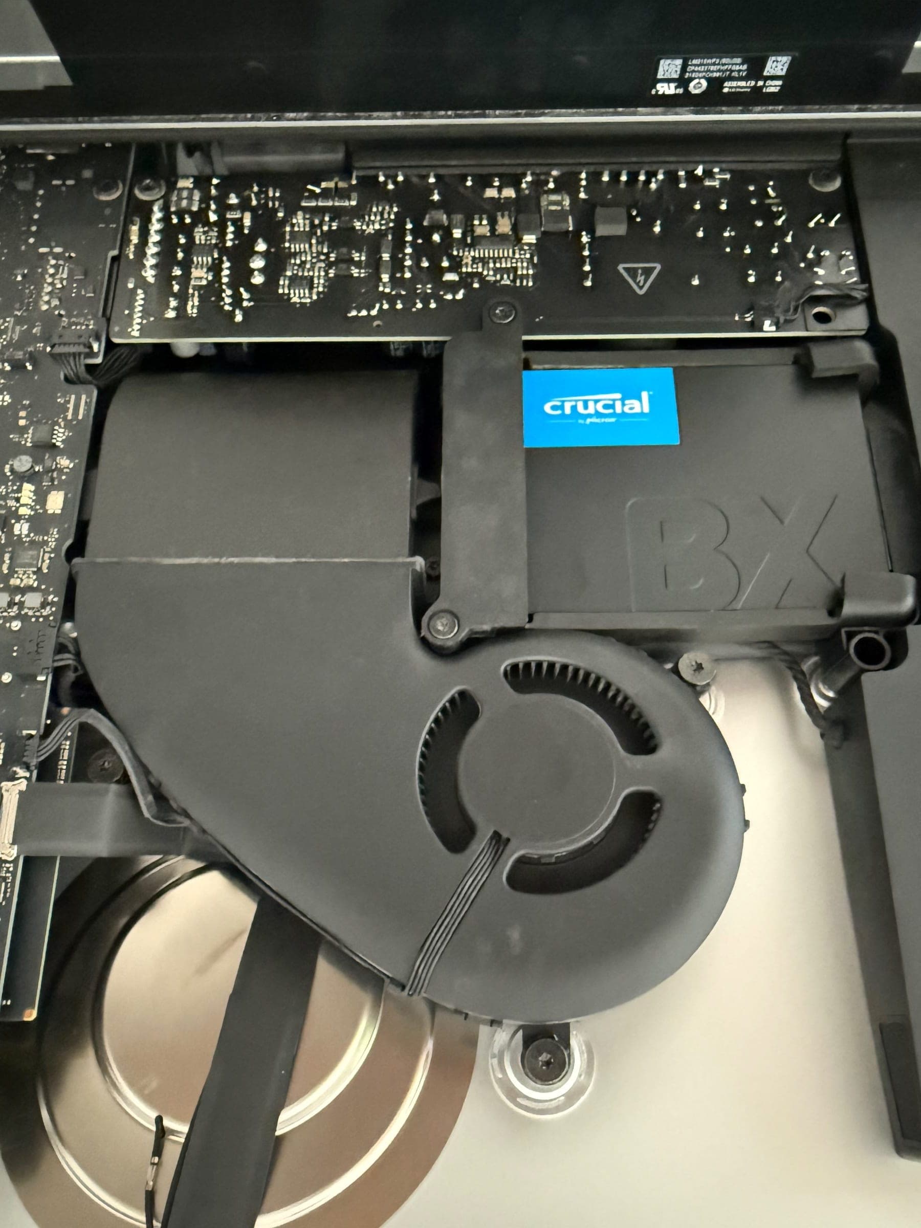 Close-up of the reinstalled iMac fan next to a Crucial BX SSD mounted in the drive bay